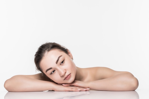 Beautiful face skincare beauty asian woman lying down with mirror reflection isolated on white wall.