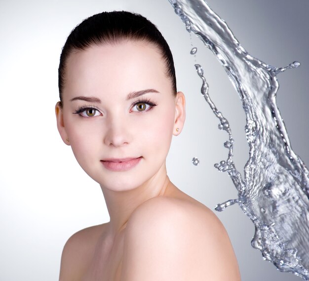 Beautiful face with clean skin and splashes of water - colored background