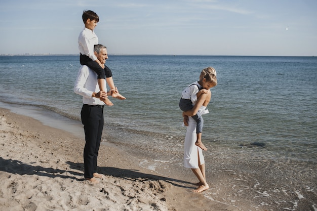 Beautiful family is walking on the coastline, parents and two sons, on the sunny summer day