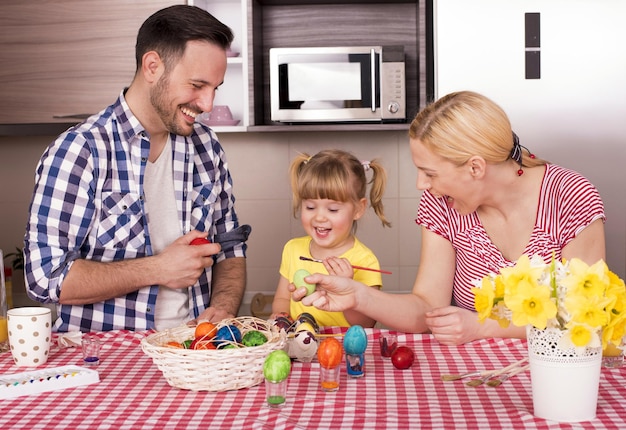 Красивая семья раскрашивает пасхальные яйца со своим ребенком