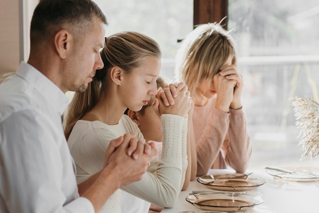 Beautiful family praying together before eating