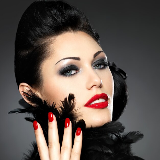 赤い爪、創造的な髪型とメイクの美しいファッションの女性