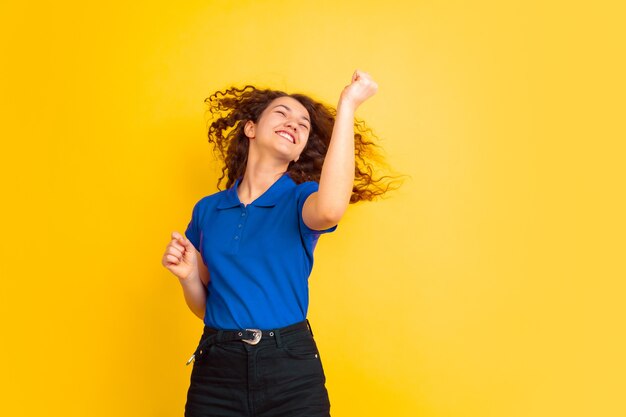 Beautiful female curly model on yellow studio wall.