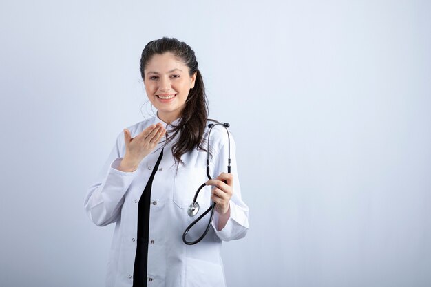 Beautiful female doctor in white coat holding stethoscope and smiling. 