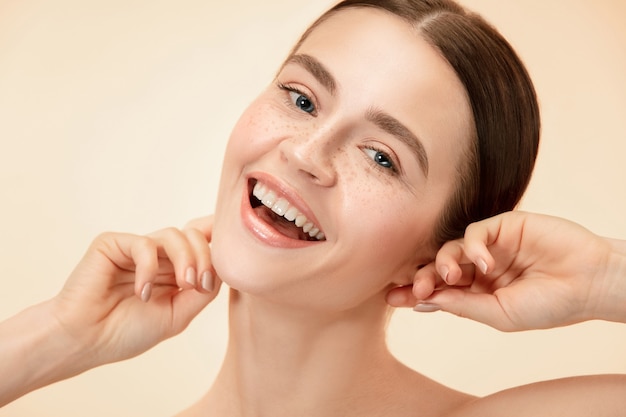 A beautiful female face. Perfect and clean skin of young caucasian woman on pastel studio background.