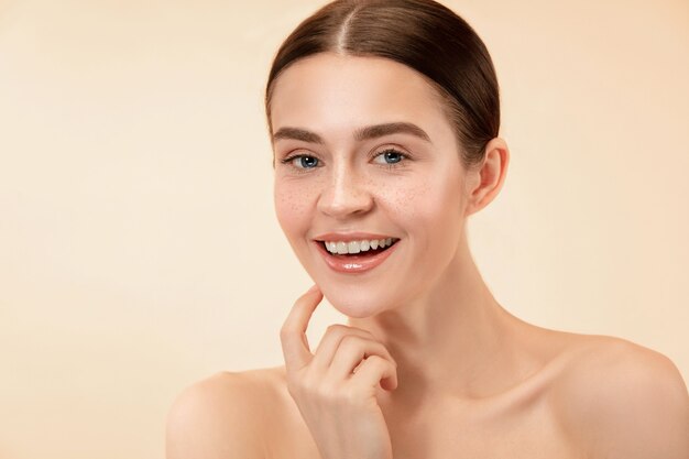 A beautiful female face. Perfect and clean skin of young caucasian woman on pastel studio background.