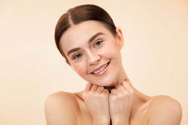 A beautiful female face. Perfect and clean skin of young caucasian woman on pastel studio background.