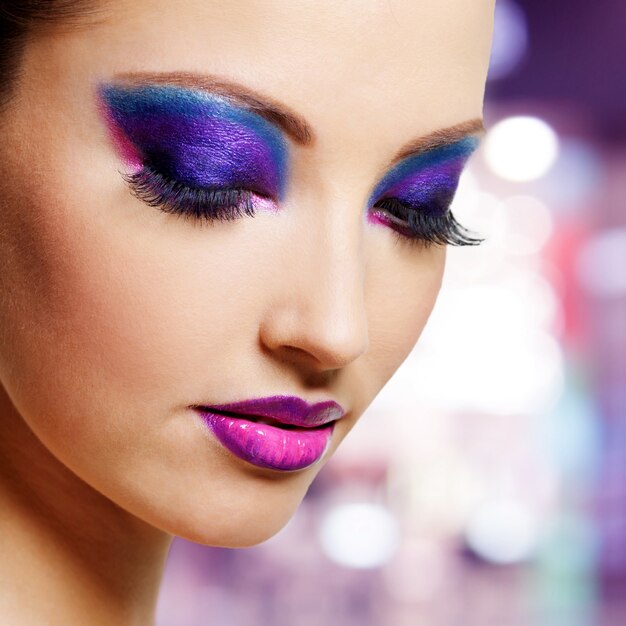 Красивое женское лицо с ярким фиолетовым модным макияжем