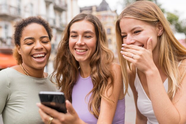 Beautiful female friends smiling at the mobile phone