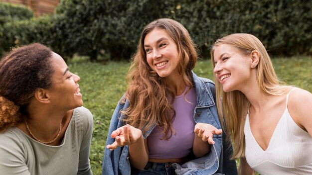 Beautiful female friends talking and sitting on the grass