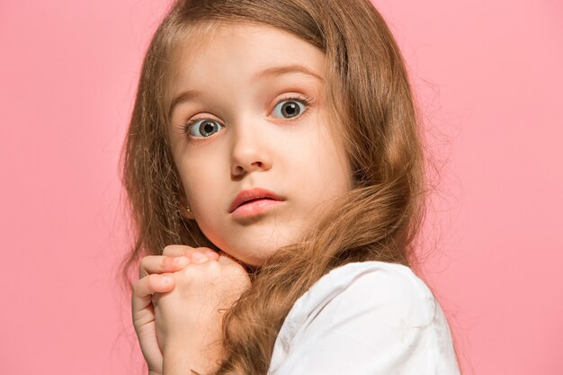 Beautiful female front portrait isolated on pink studio background. Young emotional surprised teen girl.