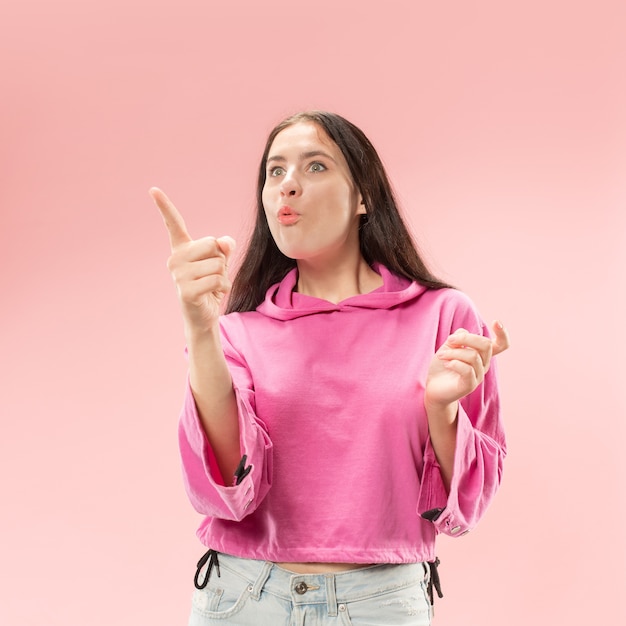 Beautiful female half-length front portrait isolated on pink studio background. Young emotional surprised woman standing with open mouth.