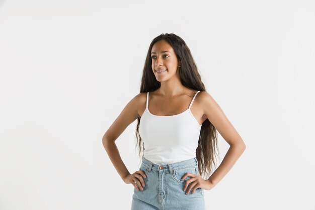 Beautiful female half-length portrait isolated on white studio background. Young emotional african-american woman with long hair. Facial expression, human emotions concept. Standing and smiling.