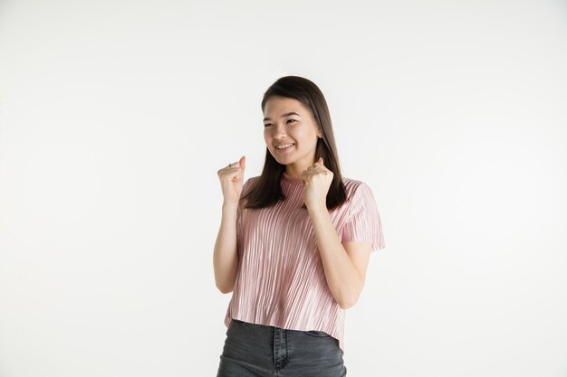 Beautiful female half-length portrait isolated on white studio background. Young emotional woman in casual clothes. Human emotions, facial expression concept. Celebrating like winner, looks happy.