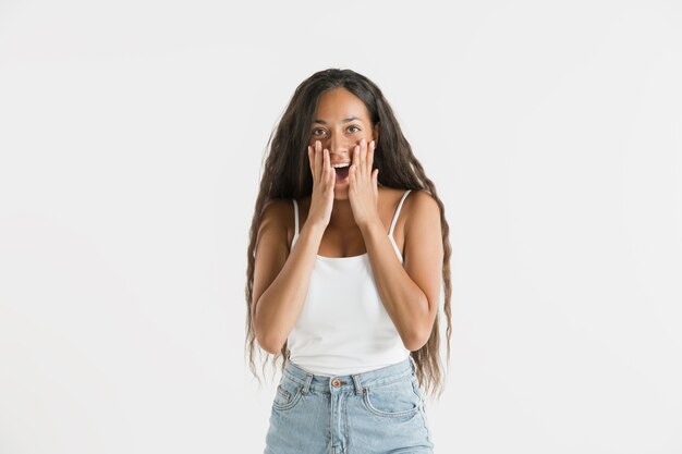 Beautiful female half-length portrait isolated on white wall. Young emotional african-american woman with long hair. Facial expression, human emotions concept. Astonished, excited.