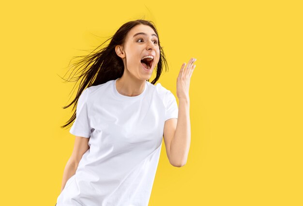 Beautiful female half-length portrait isolated on yellow studio background. Young smiling woman. Facial expression, summer, weekend, resort concept. Trendy colors.