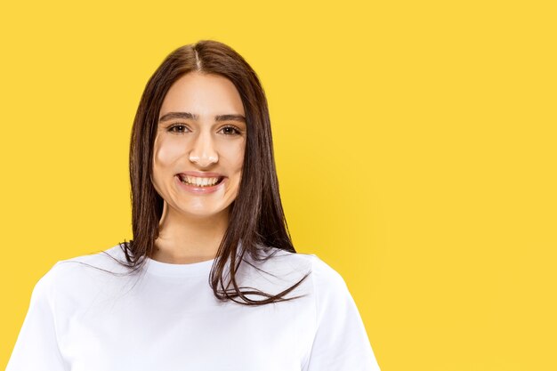 Beautiful female half-length portrait isolated on yellow studio