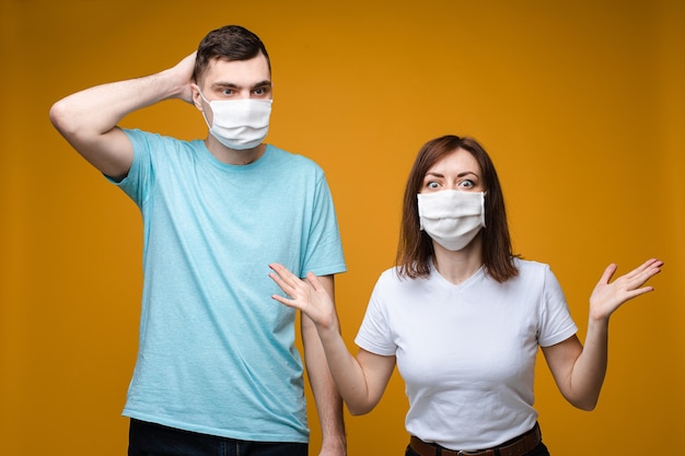 Beautiful female and handsome male stands near each other in a white and blue t-shirts and white medical masks and wants to be healthy