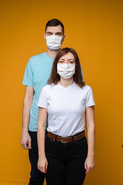 美しい女性とハンサムな男性が白と青のTシャツと白い医療用マスクで互いに近くに立っています