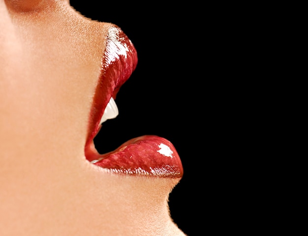 Free photo beautiful female lips. gloss lipstick. black background. healthy leather.