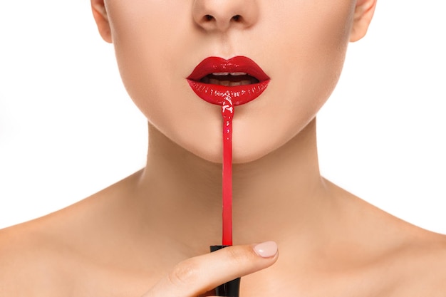 赤い化粧と白のブラシで美しい女性の唇。メイクアップアーティストの作業プロセス