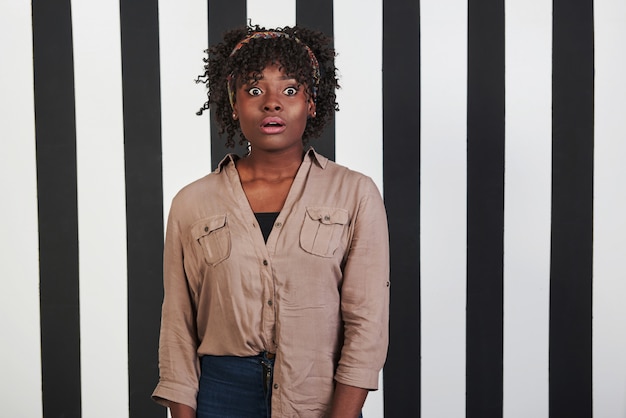 Beautiful female portrait on the black and blue stripes type background. African american girl makes shocked face