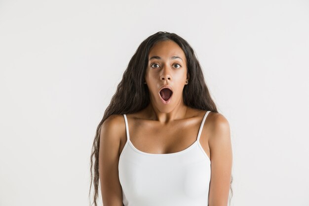 孤立した美しい女性の肖像画。長い髪の若い感情的なアフリカ系アメリカ人の女性。顔の表情、人間の感情の概念。びっくり、興奮。