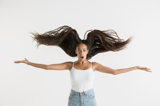 Bellissimo ritratto femminile isolato. giovane donna afro-americana emotiva con i capelli lunghi. espressione facciale, concetto di emozioni umane. si sente pazzo felice, saltando.