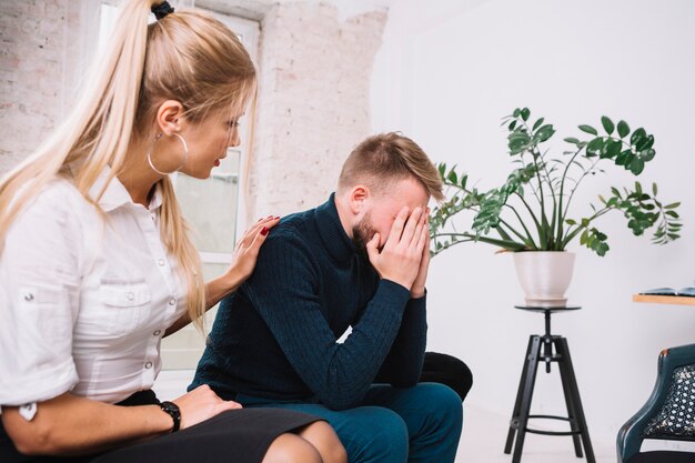 Beautiful female psychologist consoling her male depressed patient in the clinic