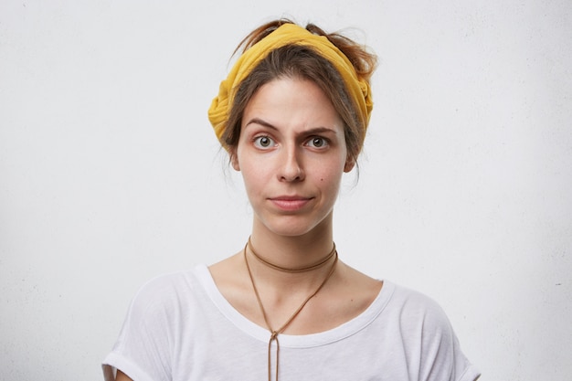 Beautiful female showing suspicion while frowning her thin eyebrows. Young woman with appealing appearance having doubts and eyes full of disbelief. Facial expressions