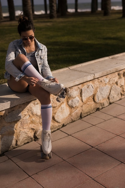 Free photo beautiful female skater tying the lace of roller skate