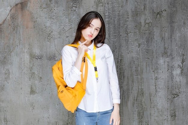 Beautiful female student with yellow backpack standing. High quality photo