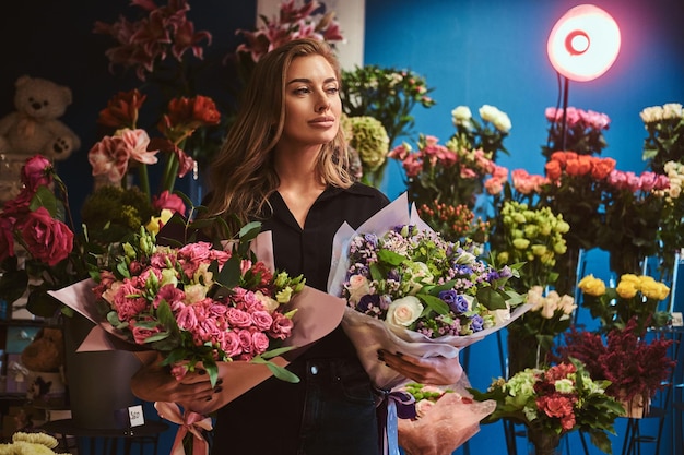 La bellissima fiorista femminile sta dimostrando fantastici bouquet al negozio di fiori