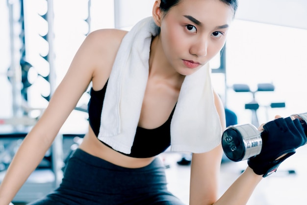 Beautiful fit Asian woman doing exercise with Dumbbell Bicep Curls healthy ideas concept in gym fitness