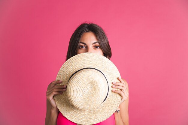 ピンクのビキニと麦わら帽子の美しいフィットの日焼けしたスポーティな女性
