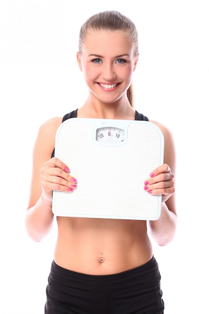 Beautiful fitness girl holding scales