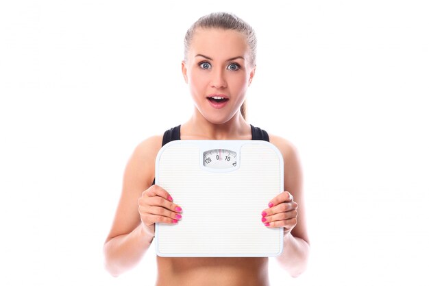 Beautiful fitness girl holding scales