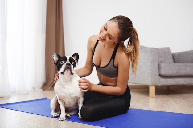 Free photo beautiful fitness girl sitting on floor with dog