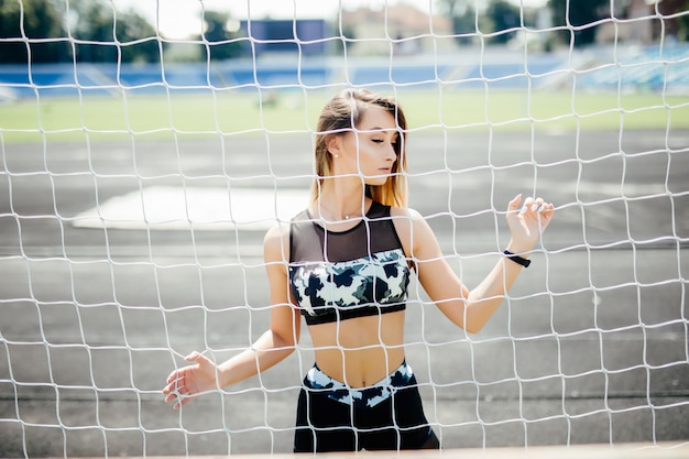 Beautiful fitness woman in sportswear posing near grid.