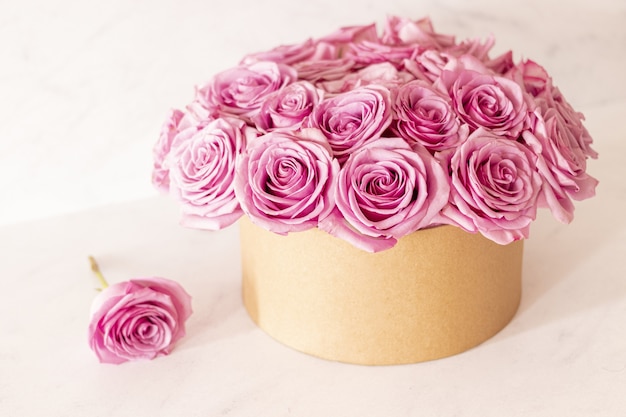 Beautiful floral bouquet with pink roses in a box on a pink background