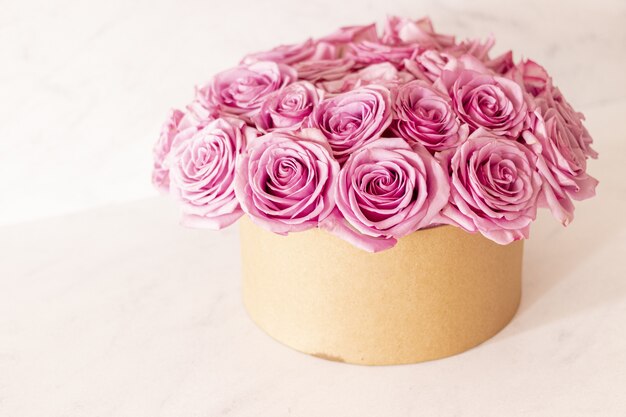 Красивый цветочный букет с розовыми розами в коробке на розовом фоне