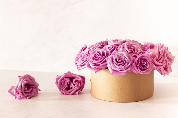 Beautiful floral bouquet with pink roses in a box on a pink background