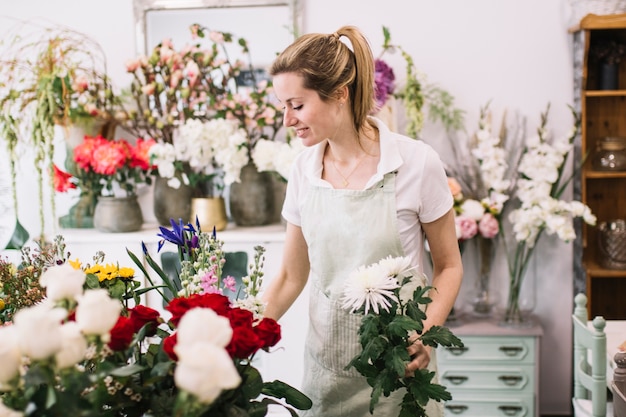 Beautiful florist arranging flowers in shop