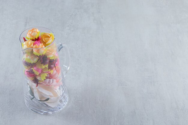 Beautiful flowers in a glass carafe, on the white table.