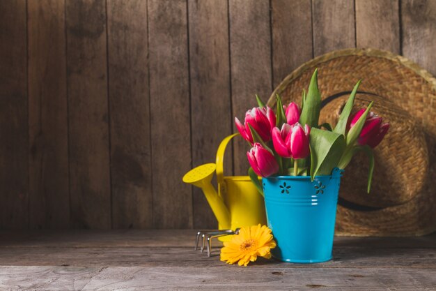 Beautiful flowers with gardening tools and wooden background