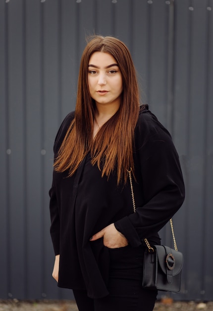 Beautiful friendly young woman with shoulder length brown hair posing outdoors