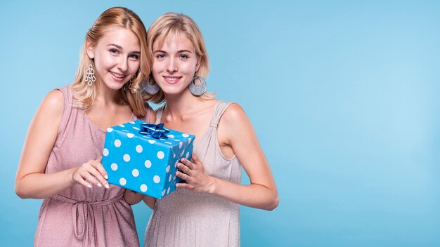 Beautiful friends holding gift box