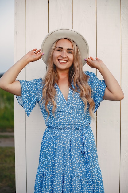 Foto gratuita bella ragazza in un vestito blu. donna in un campo estivo.