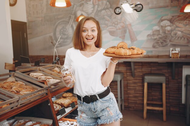 Красивая девушка покупает булочки в пекарне
