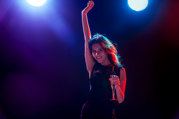 The beautiful girl dancing at the party and drinking champagne